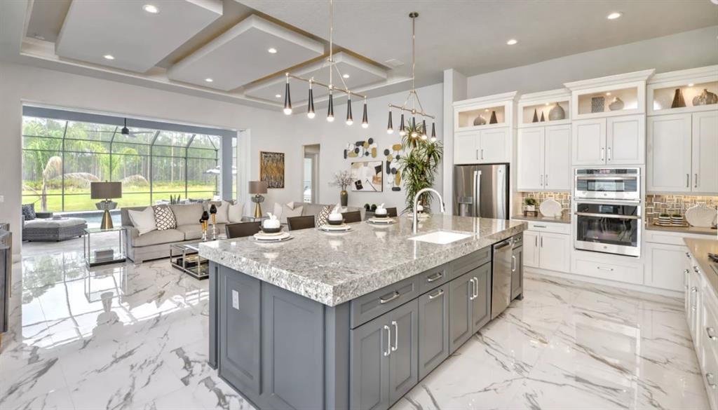 A modern kitchen with a gray island and white cabinets overlooks a living area and pool — 9 BROADWATER ROAD, ORMOND BEACH, FL