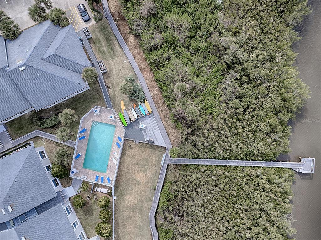 An aerial view shows a swimming pool, a wooden boardwalk, and several kayaks near trees — 4870 S. ATLANTIC AVE, UNIT 2040, NEW SMYRNA BEACH, FL