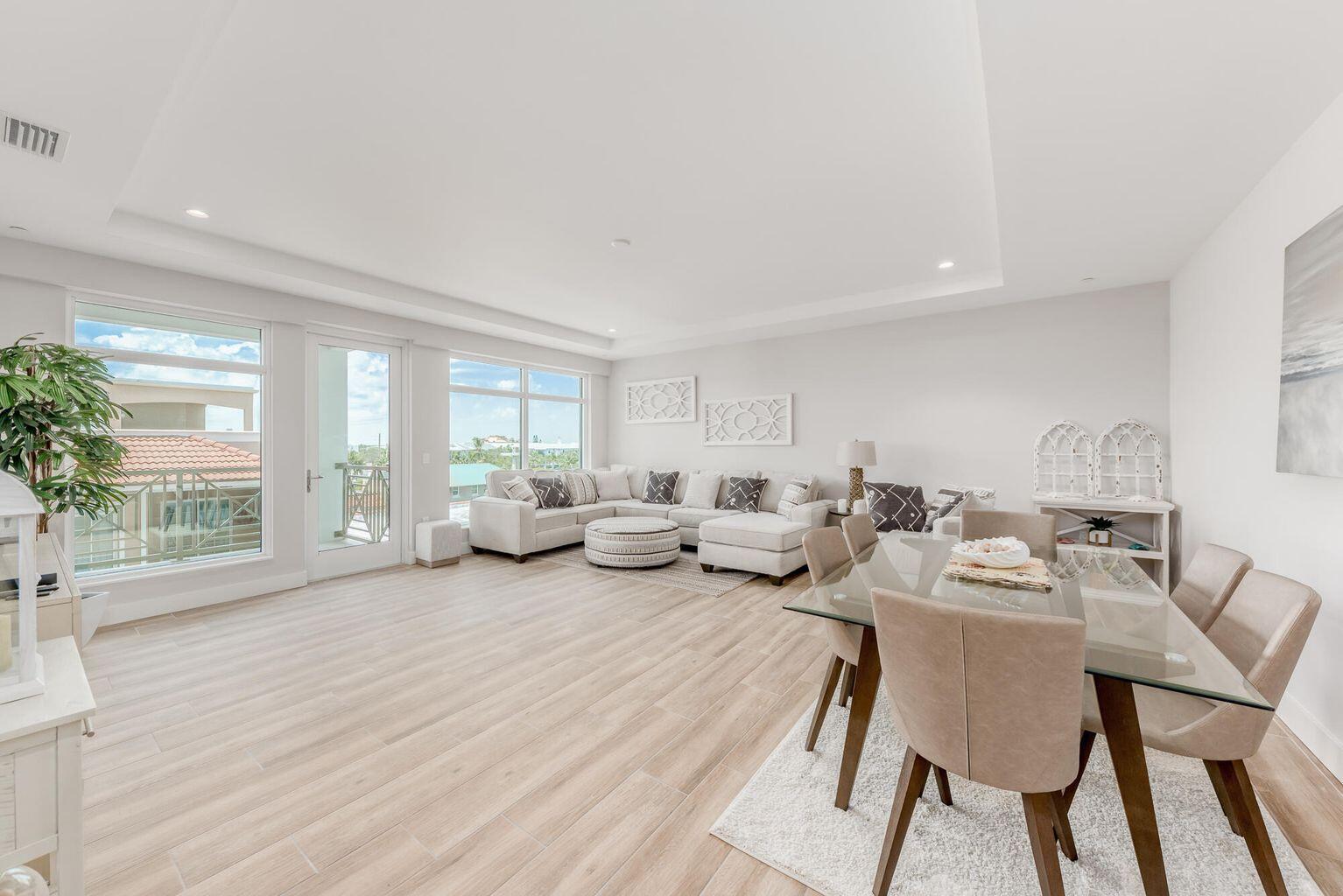 A bright open-concept living and dining area with light wood-look tile flooring and large windows — 41 SW Seminole Street # 410, Stuart FL 34994, STUART, FL