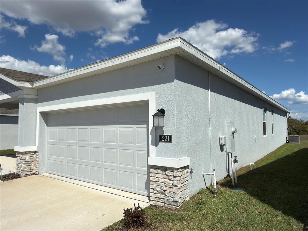 A modern kitchen features white cabinets, stainless steel appliances, a quartz island, and tile flooring — 521 REGGIE ROAD, WINTER HAVEN, FL