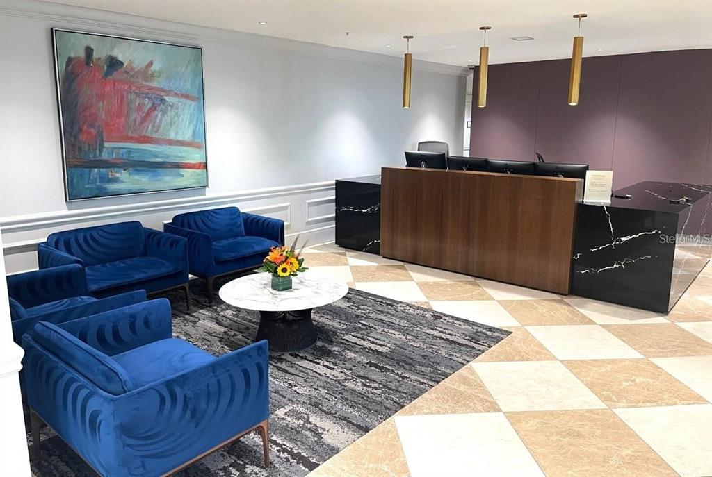 A modern office lobby features blue velvet chairs, a marble coffee table, and a reception desk — 450 KNIGHTS RUN AVENUE UNIT 102, TAMPA, FL