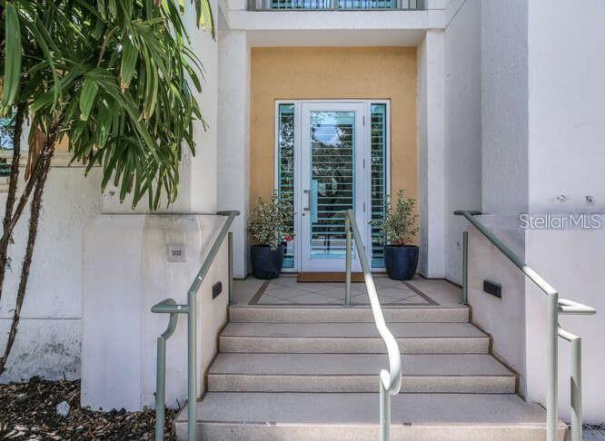 A set of concrete stairs leads to a white front door with glass panels — 450 KNIGHTS RUN AVENUE UNIT 102, TAMPA, FL