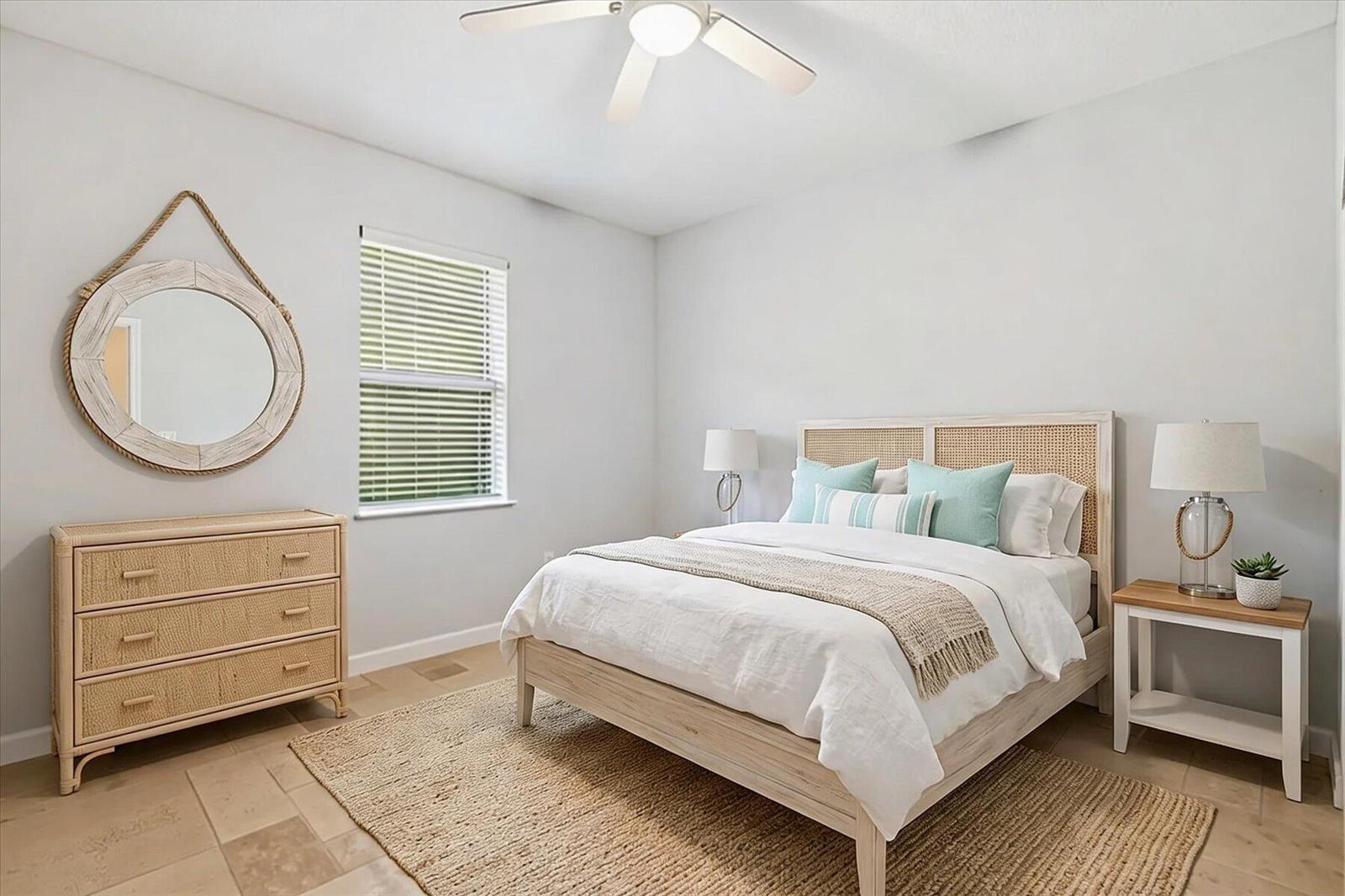 A bedroom features a cane headboard, a matching dresser, a round mirror, and a rug — VERO BEACH, FL