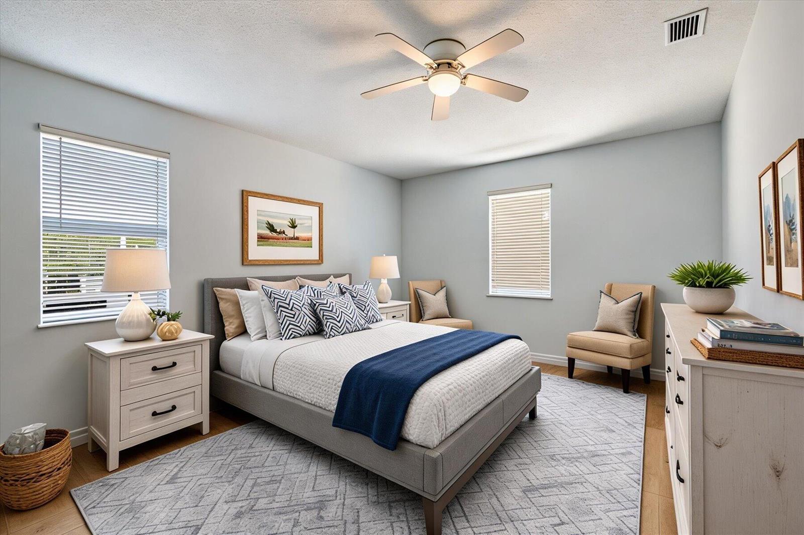 A bedroom features a gray bed, two nightstands, two chairs, and a patterned area rug — VERO BEACH, FL