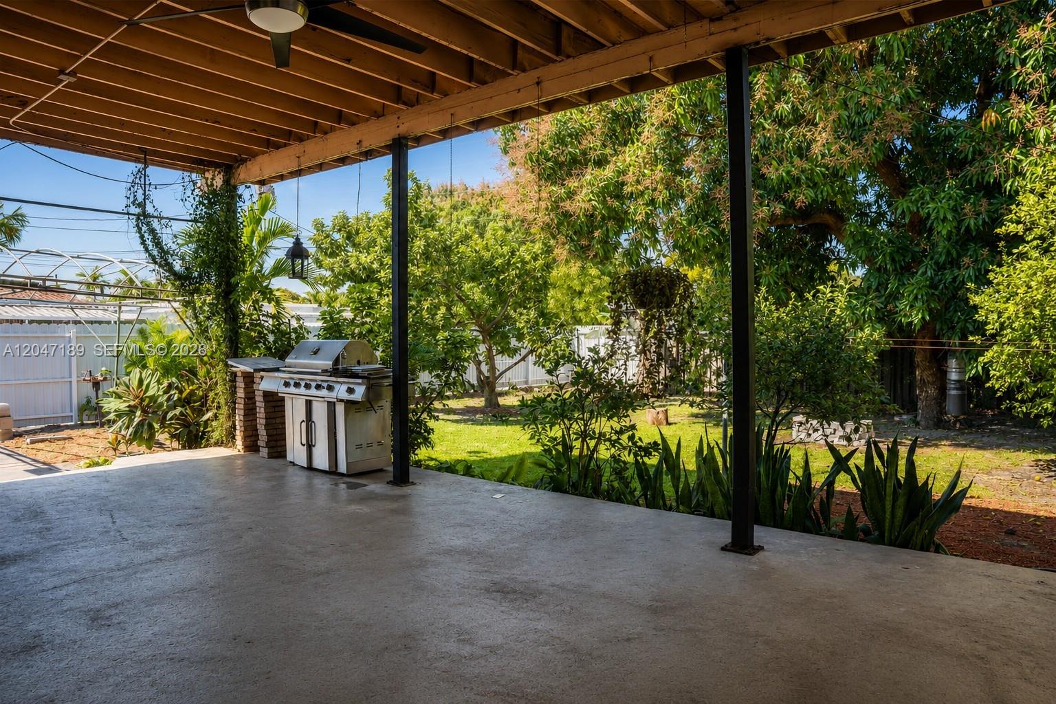 A covered concrete patio features a stainless steel grill and views of a backyard — 861 W 32nd St, Hialeah FL 33012, HIALEAH, FL