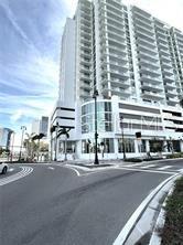 A low-angle view of a tall, modern white high-rise building situated at a street intersection — 301 QUAY COMMONS UNIT 904, SARASOTA, FL