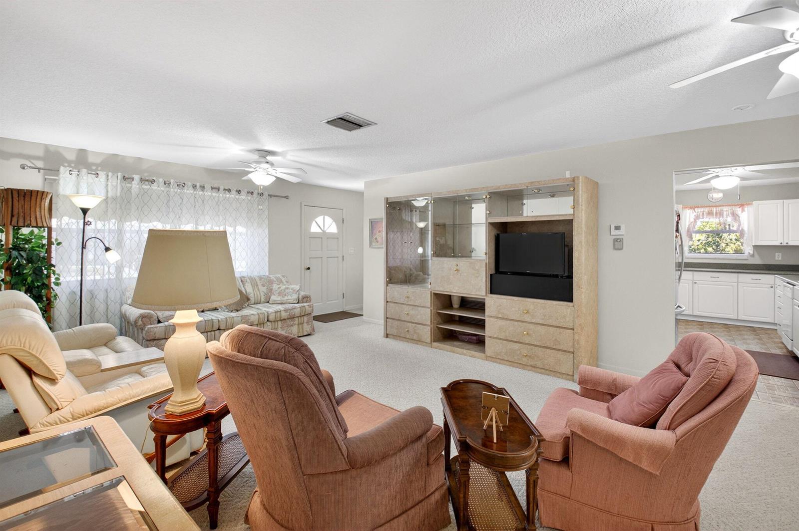 A living room features a large entertainment center, two armchairs, a sofa, and carpeted floors — 700 Canal Way, Boynton Beach FL 33426, BOYNTON BEACH, FL