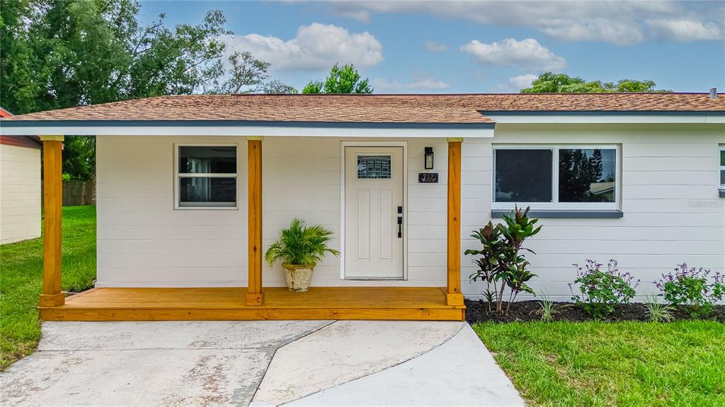A white house exterior features a wooden porch with two support posts and a front door — 717 W WINIFRED STREET, AVON PARK, FL
