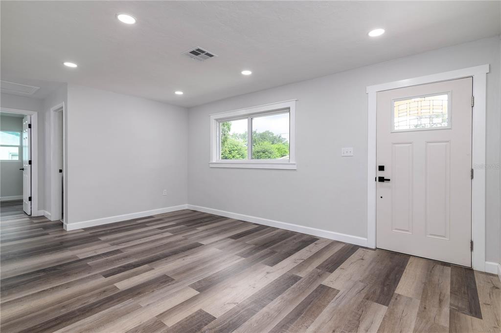 An empty room features light gray walls, recessed lighting, and wood-look flooring — 717 W WINIFRED STREET, AVON PARK, FL