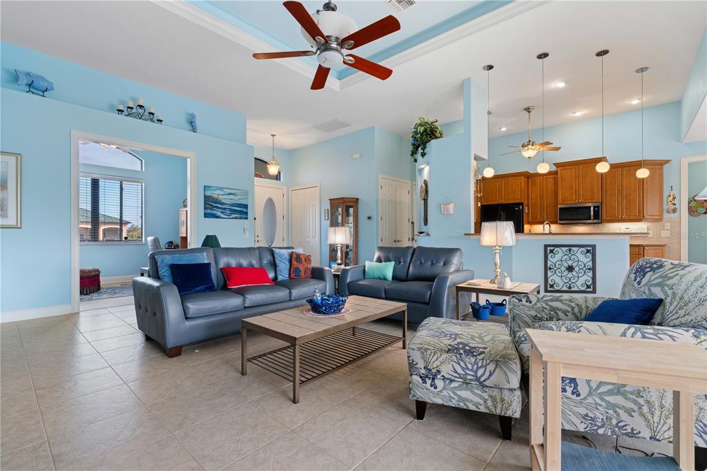 A living room with blue walls, tile floors, and a kitchen in the background — 17157 MINT LANE, PUNTA GORDA, FL