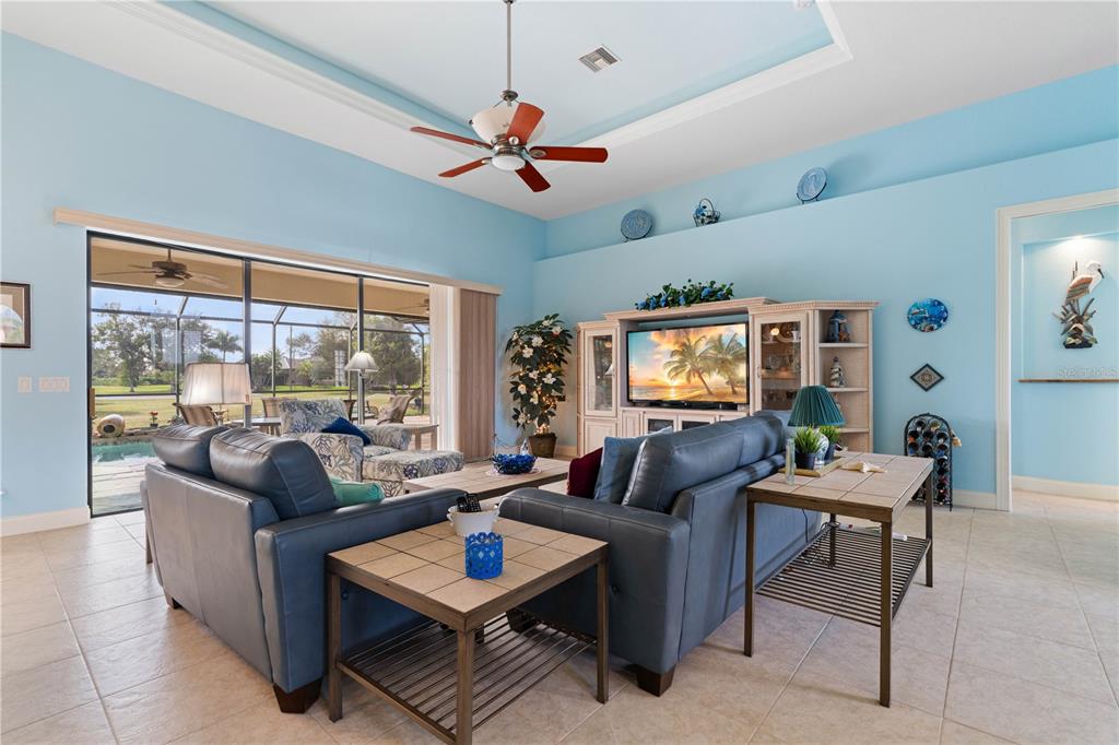 A living room features blue walls, a tray ceiling, tile floors, and a sliding glass door — 17157 MINT LANE, PUNTA GORDA, FL