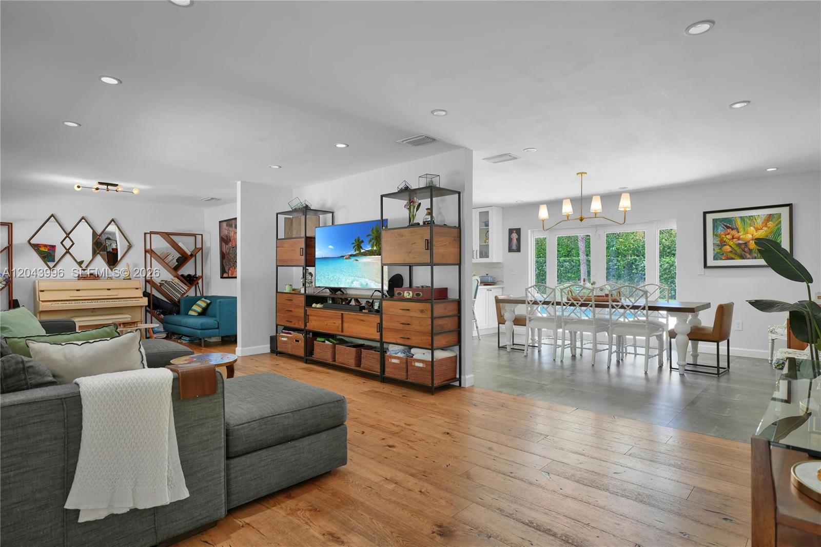 A living room with wood floors flows into a dining area with tile flooring — 5721 SW 59th Ct, South Miami FL 33143, SOUTH MIAMI, FL