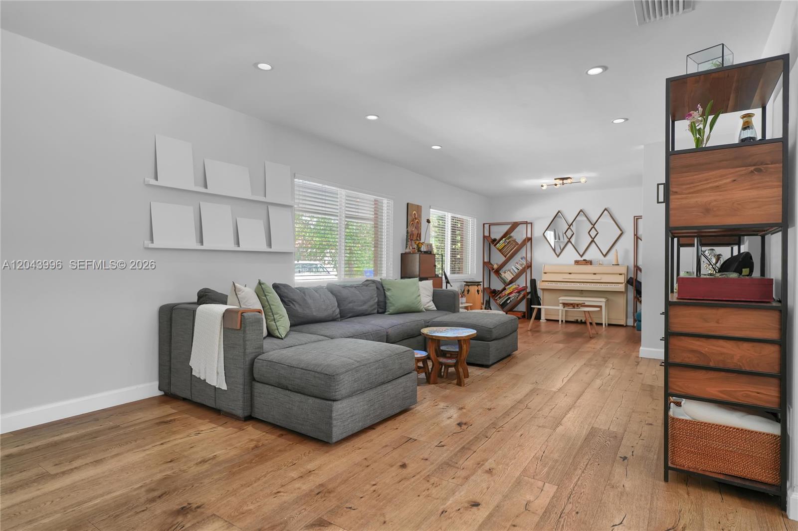 A living room features a grey sectional sofa, wood flooring, and a piano — 5721 SW 59th Ct, South Miami FL 33143, SOUTH MIAMI, FL