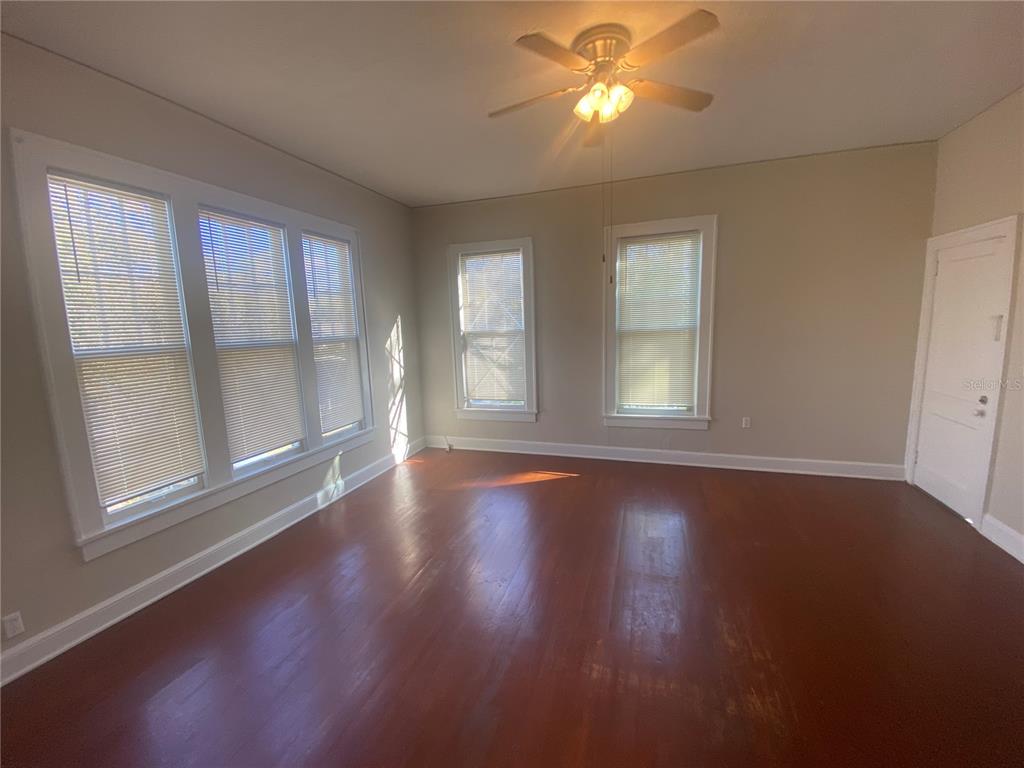 A room with hardwood floors, a ceiling fan, and multiple windows with blinds — 1120 WEBSTER STREET UNIT 4, LEESBURG, FL