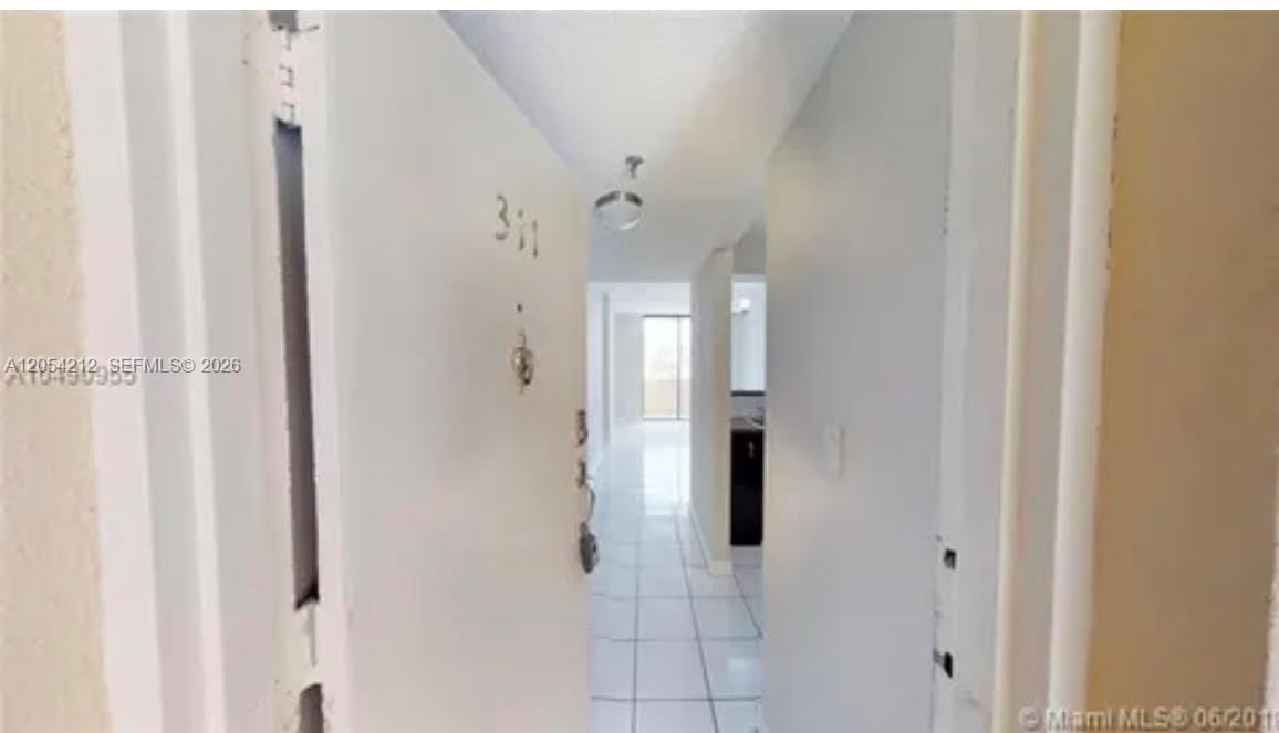 A view through an open doorway into a tiled apartment hallway with a distant window — 501 SW 1st St # 311, Miami FL 33130, MIAMI, FL