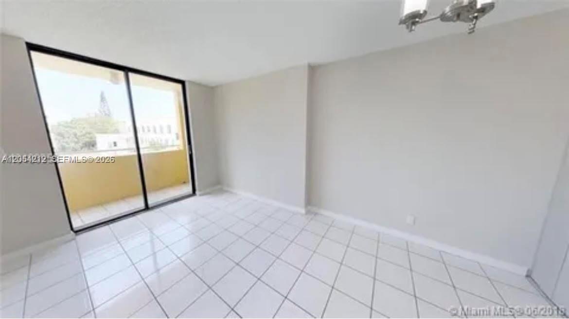 An empty room features white tile flooring, light-colored walls, and a sliding glass door — 501 SW 1st St # 311, Miami FL 33130, MIAMI, FL