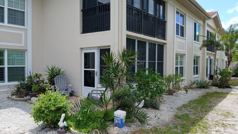 A multi-story apartment building exterior features screened-in patios and landscaping on a gravel ground — 10350 IMPERIAL POINT DRIVE W UNIT 8, LARGO, FL