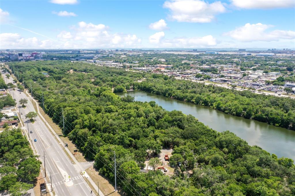 An aerial view shows a road running alongside a wooded area and a river — 7012 N WILLOW AVENUE, TAMPA, FL