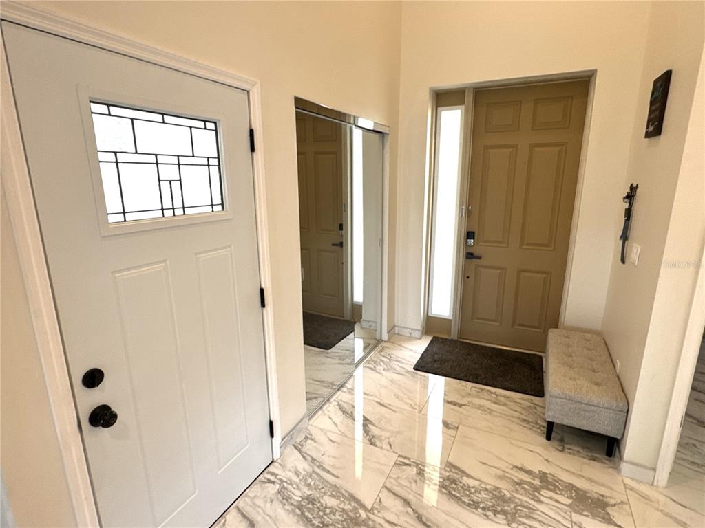 An entryway features white marble-look tile flooring, a mirrored closet, and two doors — 1501 HELENE AVENUE, ENGLEWOOD, FL