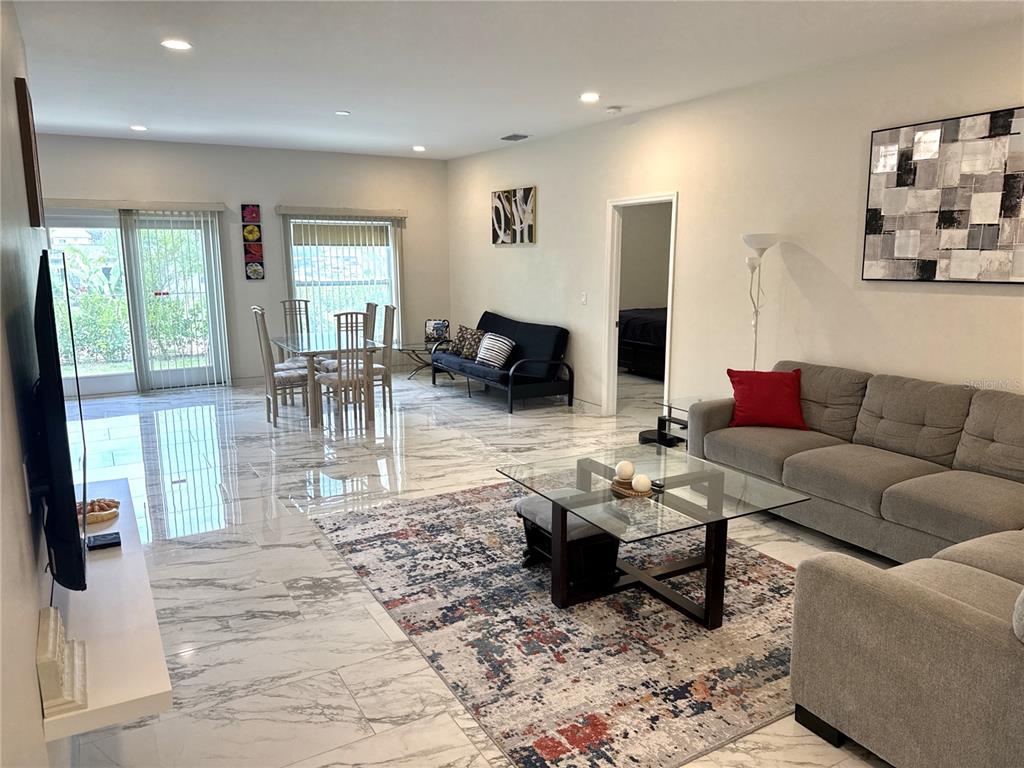 A living and dining area features marble-look tile flooring, a glass coffee table, and furniture — 1501 HELENE AVENUE, ENGLEWOOD, FL