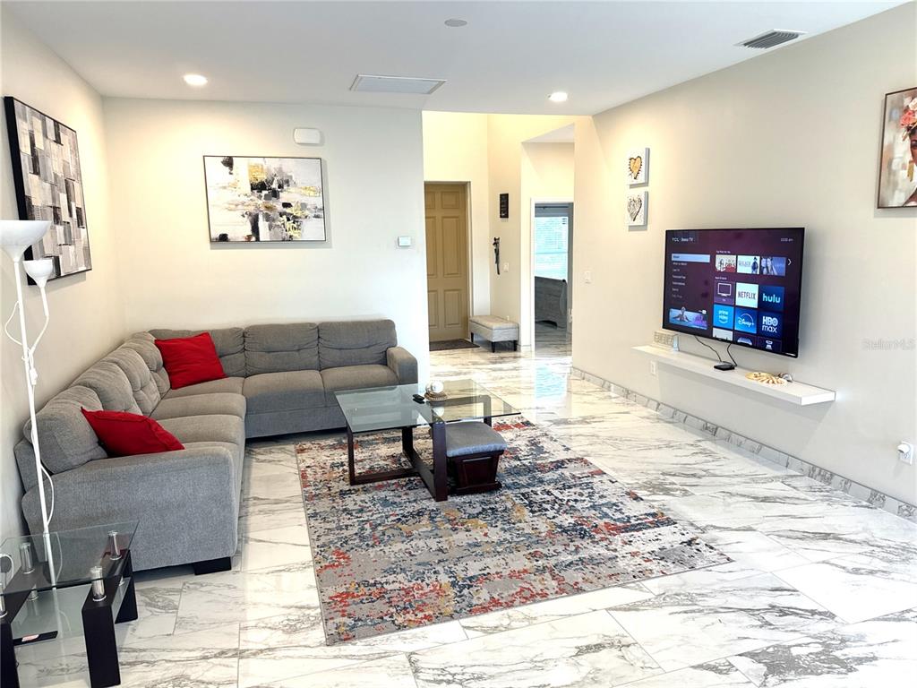 A living room features a gray sectional sofa, a glass coffee table, and a wall-mounted television — 1501 HELENE AVENUE, ENGLEWOOD, FL