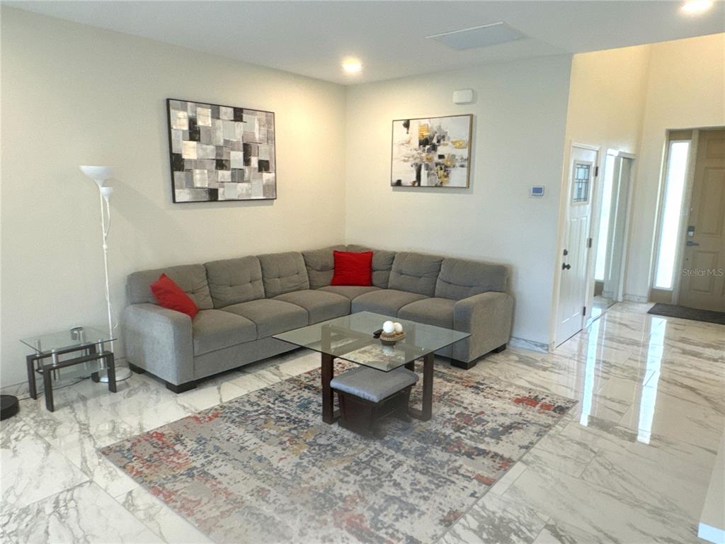A living room features a gray sectional sofa, glass coffee table, and area rug — 1501 HELENE AVENUE, ENGLEWOOD, FL