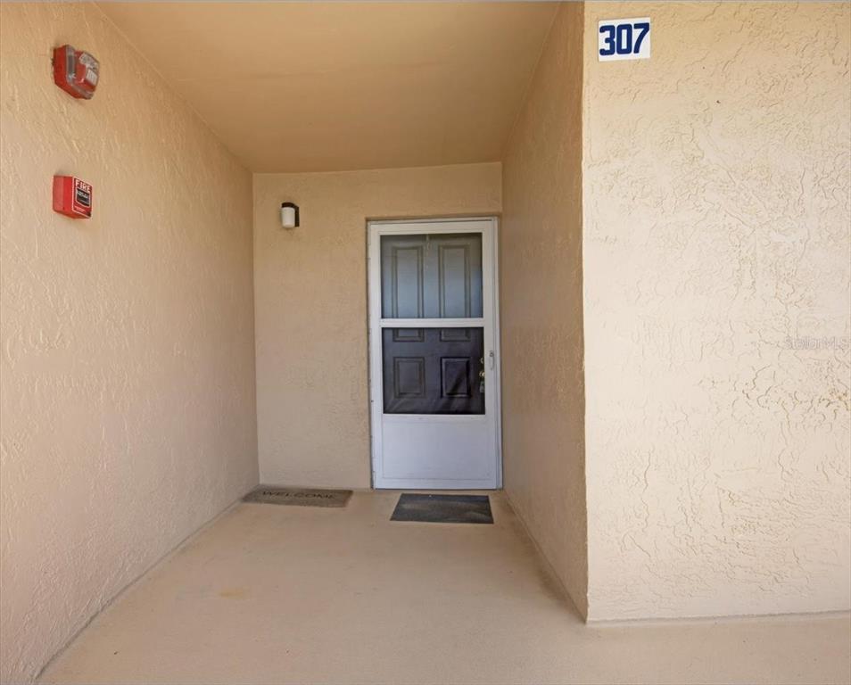 An exterior view of a residential apartment entrance with a white door and unit number 307 — 3360 OCEAN SHORE BOULEVARD UNIT 3070, ORMOND BEACH, FL