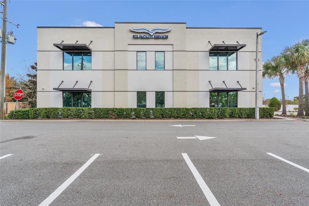A two-story commercial building with a light-colored facade, dark window awnings, and a parking lot — 131 S COUNTRY CLUB ROAD, LAKE MARY, FL