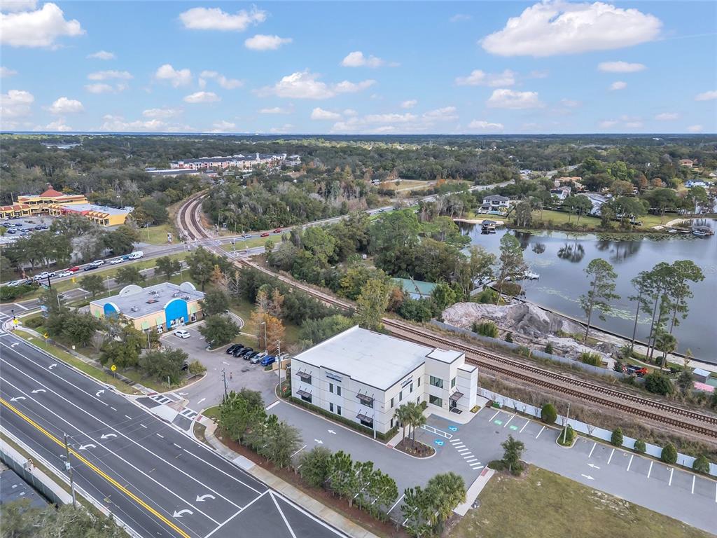 An aerial view shows a commercial building, a parking lot, railroad tracks, and a lake — 131 S COUNTRY CLUB ROAD, LAKE MARY, FL