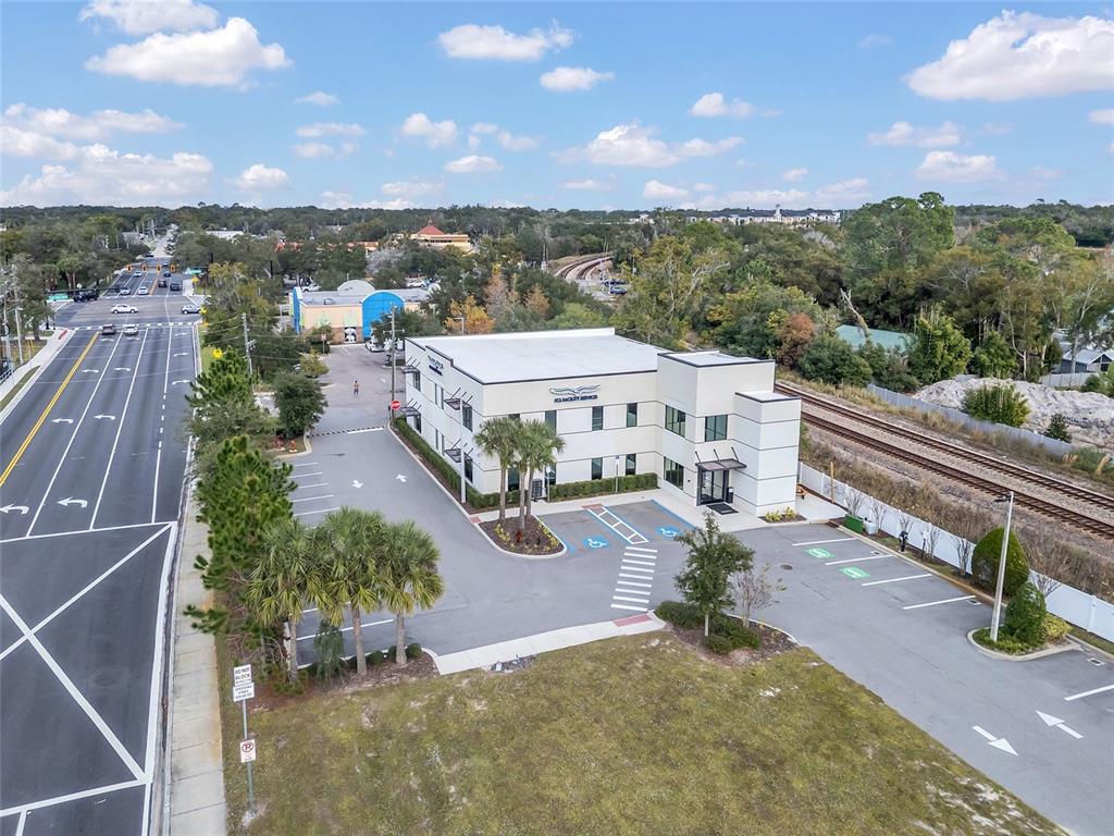 An aerial view shows a two-story commercial building with a parking lot and railroad tracks — 131 S COUNTRY CLUB ROAD, LAKE MARY, FL