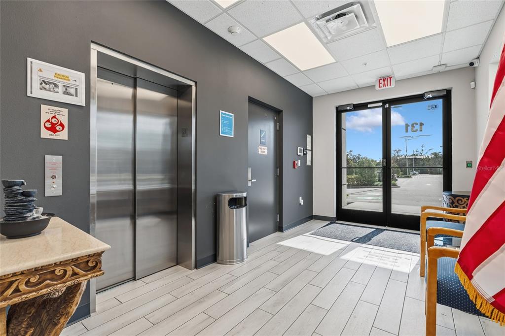 A building lobby features an elevator, a glass door entrance, and wood-look tile flooring — 131 S COUNTRY CLUB ROAD, LAKE MARY, FL