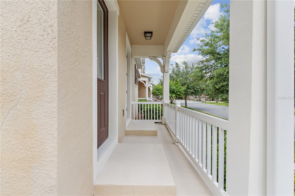 A covered front porch with a white railing overlooks a suburban street — 8012 BLUEJACK OAK DRIVE, WINTER GARDEN, FL