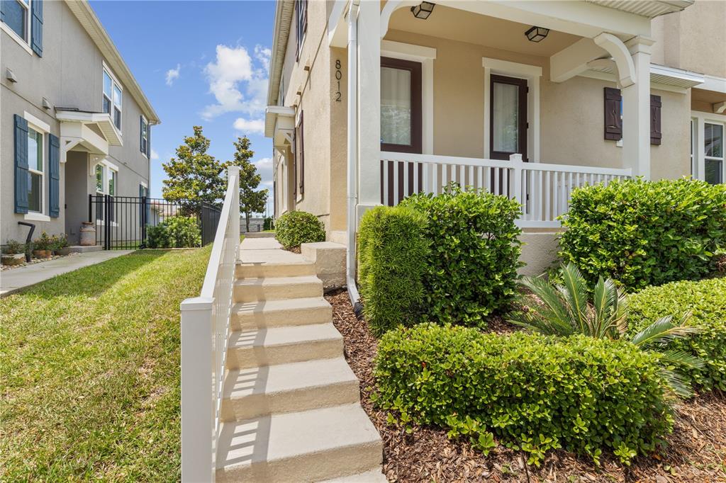 A concrete staircase leads to the front porch of a tan house with white railings — 8012 BLUEJACK OAK DRIVE, WINTER GARDEN, FL