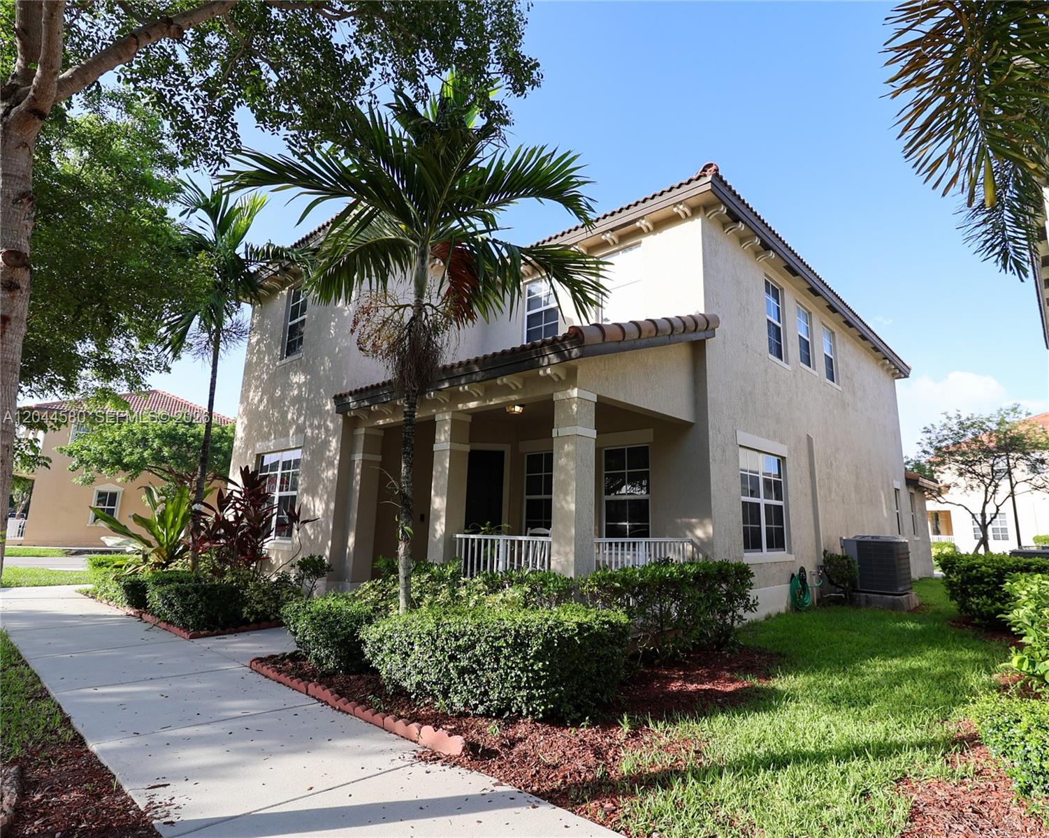 A two-story stucco house with a covered front porch and a palm tree in front — 24623 SW 115th Ct, Homestead FL 33032, HOMESTEAD, FL