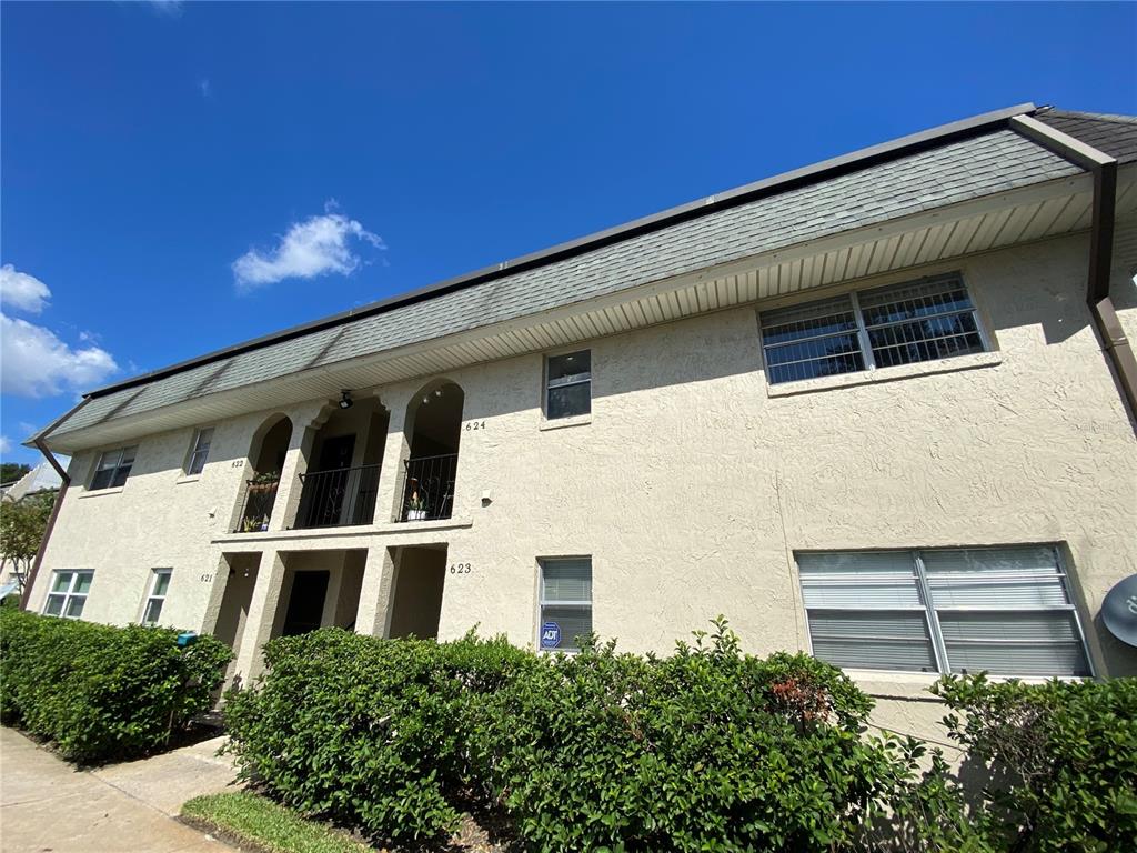A two-story apartment building exterior features stucco walls, arched entryways, and a shingled mansard roof — 623 E SAN SEBASTIAN COURT UNIT 623, ALTAMONTE SPRINGS, FL