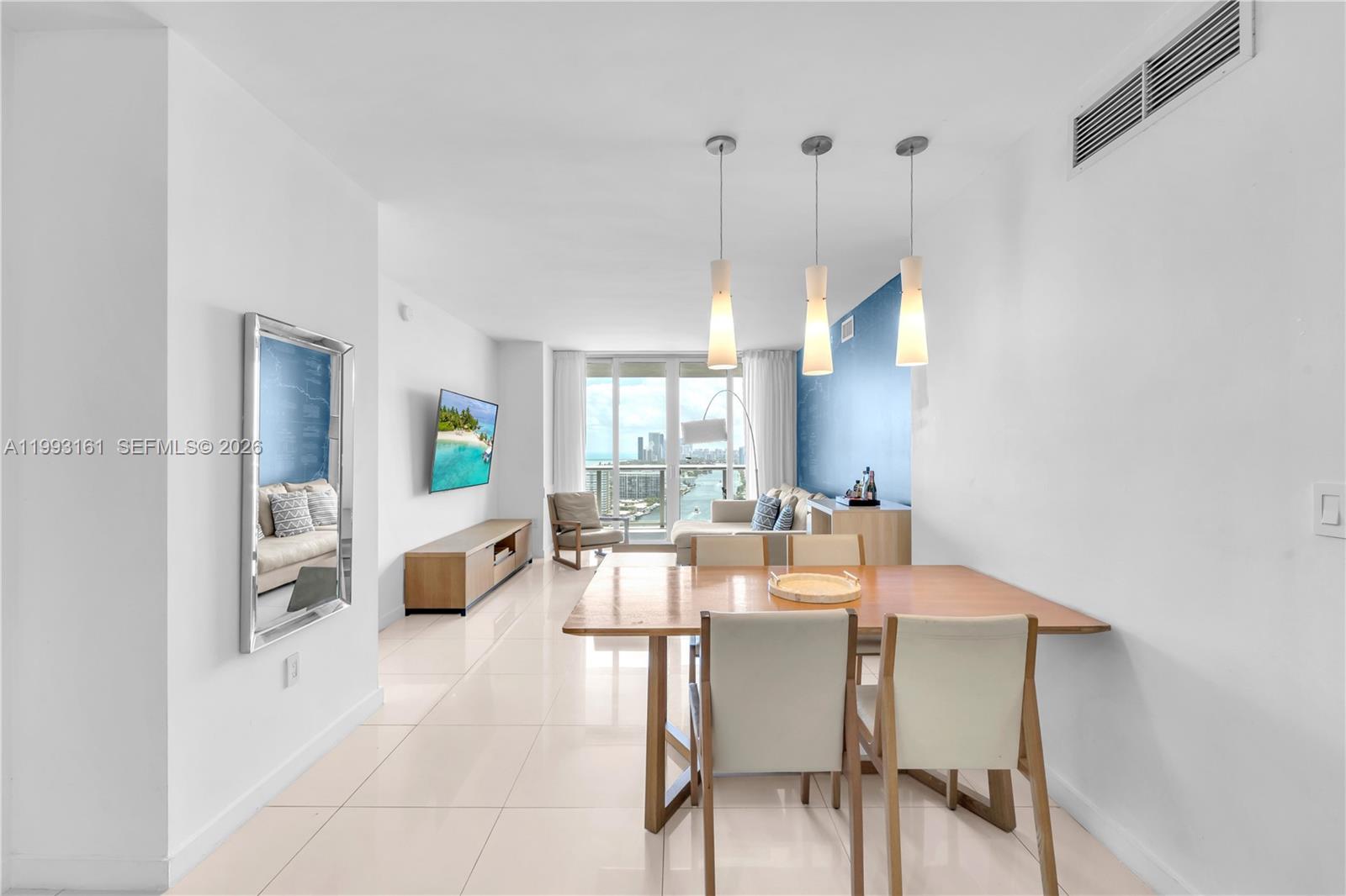 A bright living and dining area features white tile floors, modern pendant lights, and a balcony — 2602 E Hallandale Beach Blvd # R2805, Hallandale Beach FL 33009, HALLANDALE BEACH, FL