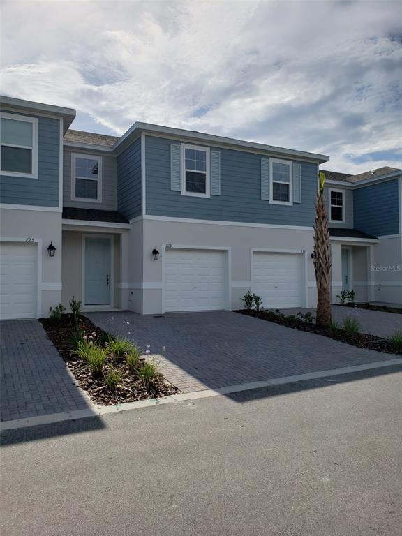 A row of two-story townhomes features blue siding, white stucco, and paved driveways — 729 MAPLE OAK DRIVE, DELAND, FL