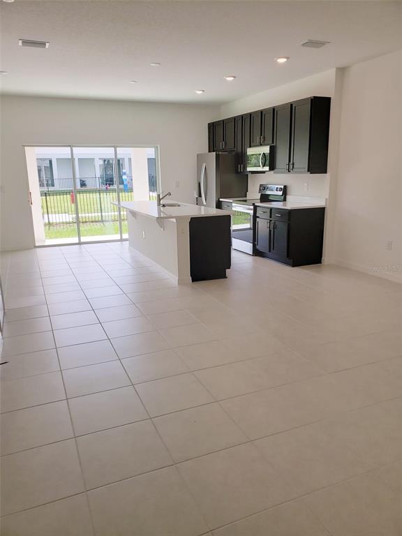 A kitchen with dark cabinets and a white island overlooks a patio through sliding doors — 729 MAPLE OAK DRIVE, DELAND, FL