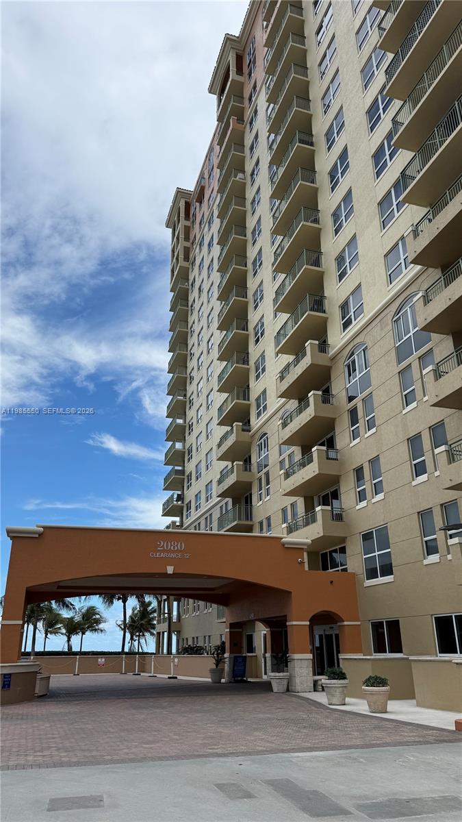 A low-angle exterior view shows a tall, multi-story apartment building with balconies and a porte-cochère — 2080 S Ocean Dr # 905, Hallandale Beach FL 33009, HALLANDALE BEACH, FL