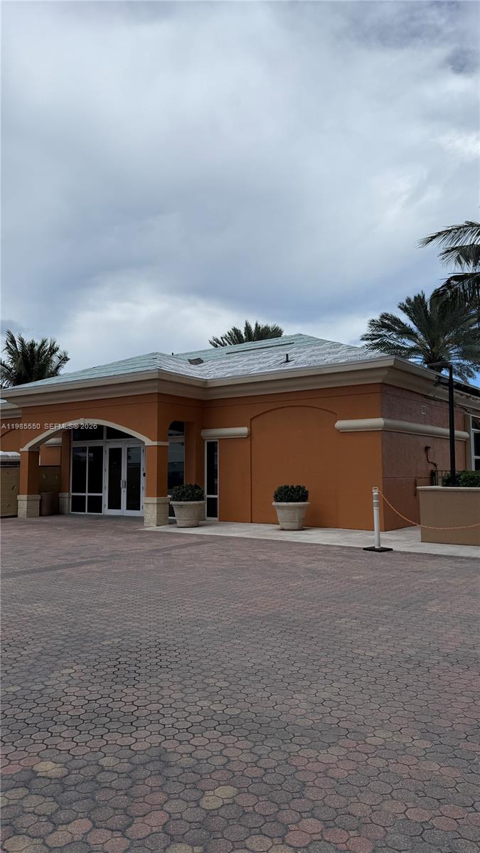 An exterior view of a single-story orange building with a paved courtyard and palm trees — 2080 S Ocean Dr # 905, Hallandale Beach FL 33009, HALLANDALE BEACH, FL