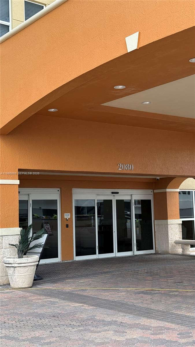 The exterior entrance of a building features an orange facade, glass doors, and a planter — 2080 S Ocean Dr # 905, Hallandale Beach FL 33009, HALLANDALE BEACH, FL