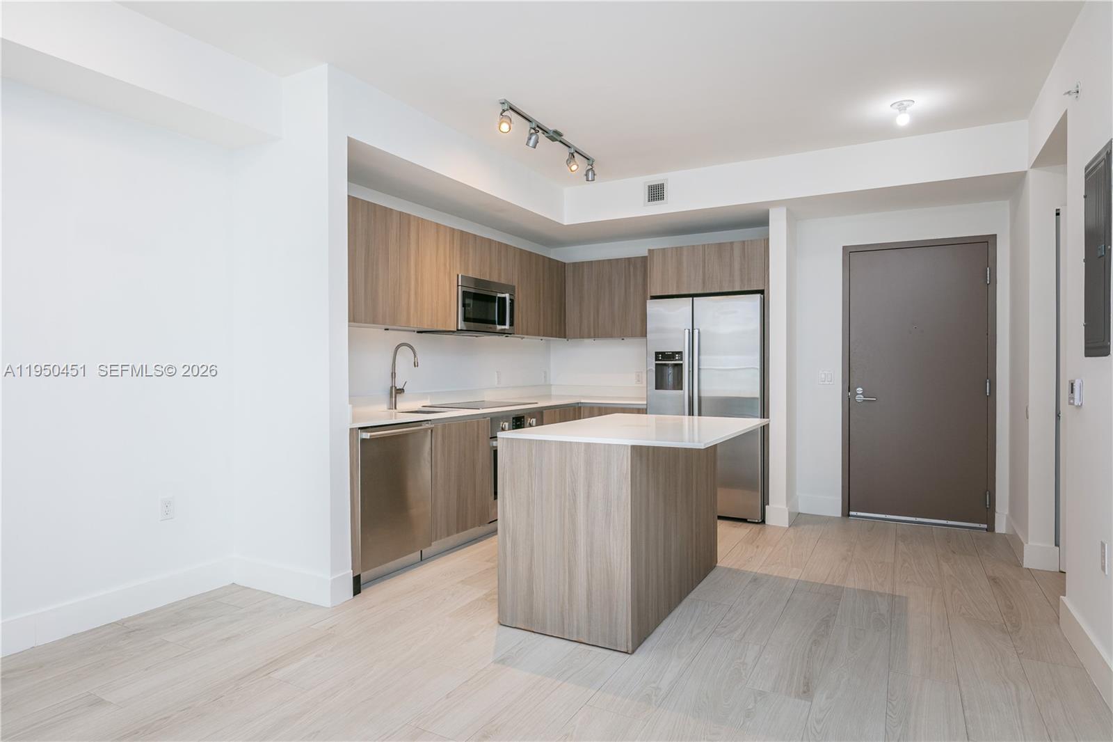 A modern kitchen features wood-grain cabinets, stainless steel appliances, and a central island — 201 SW 17th Rd # 303, Miami FL 33129, MIAMI, FL