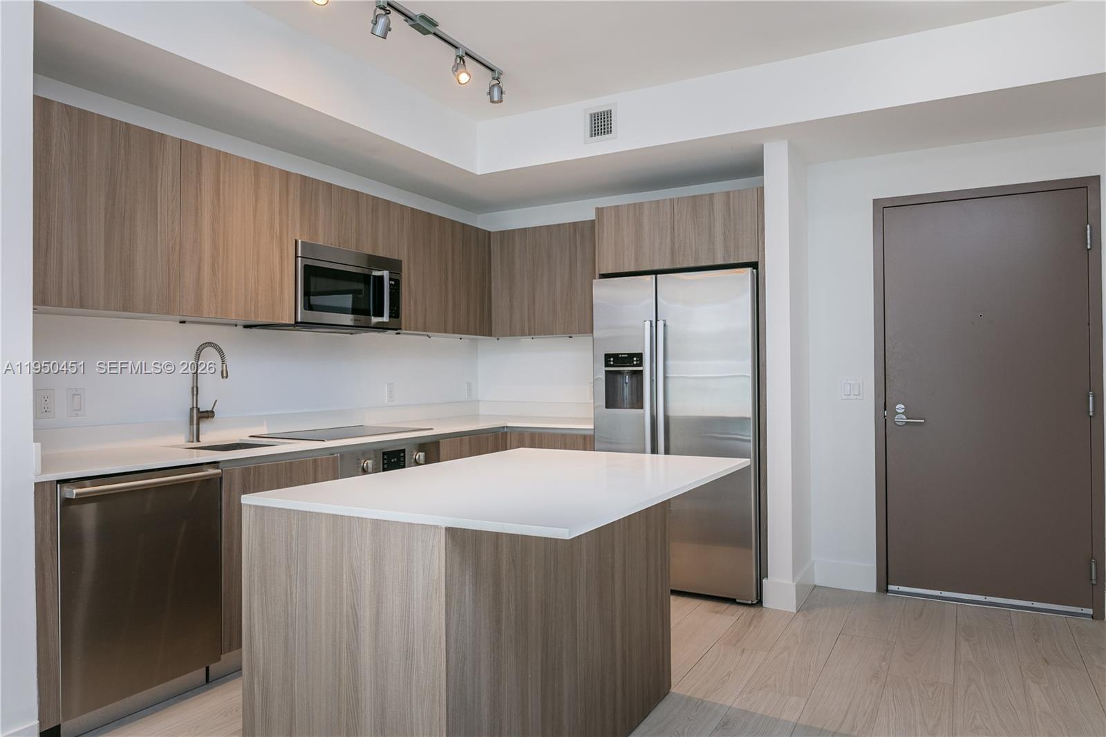 A modern kitchen features wood-grain cabinets, stainless steel appliances, and a white quartz island — 201 SW 17th Rd # 303, Miami FL 33129, MIAMI, FL