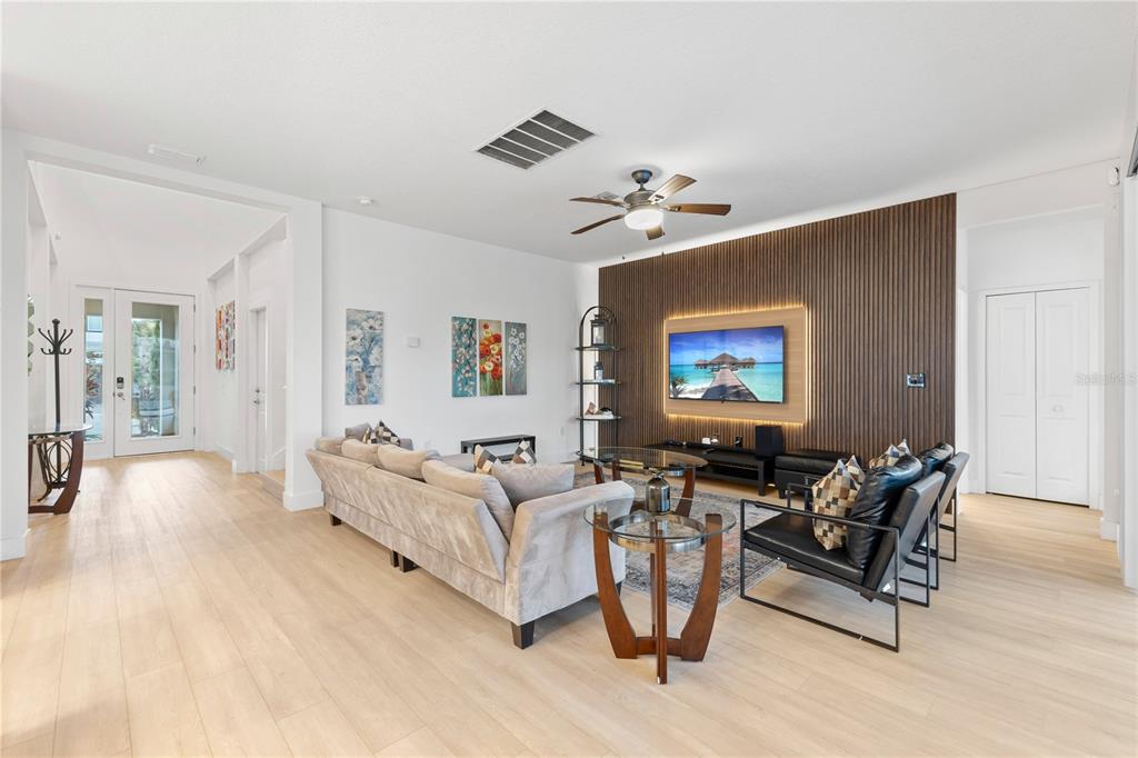 A living room features light wood floors, a slat wood accent wall, and a ceiling fan — 2694 CALISTOGA AVENUE, KISSIMMEE, FL