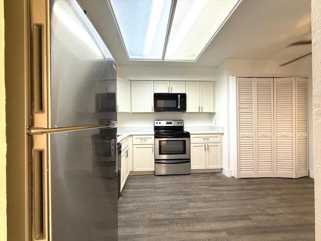 A kitchen features white cabinets, stainless steel appliances, and gray wood-look flooring — 4570 NW 18th Avenue # 609, Deerfield Beach FL 33064, DEERFIELD BEACH, FL
