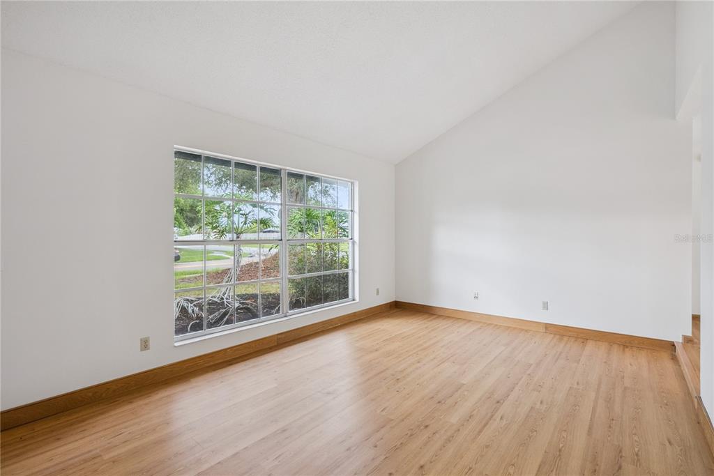 An empty room with light wood flooring, white walls, a vaulted ceiling, and a large window — 1298 MADELENA AVENUE, WINTER SPRINGS, FL
