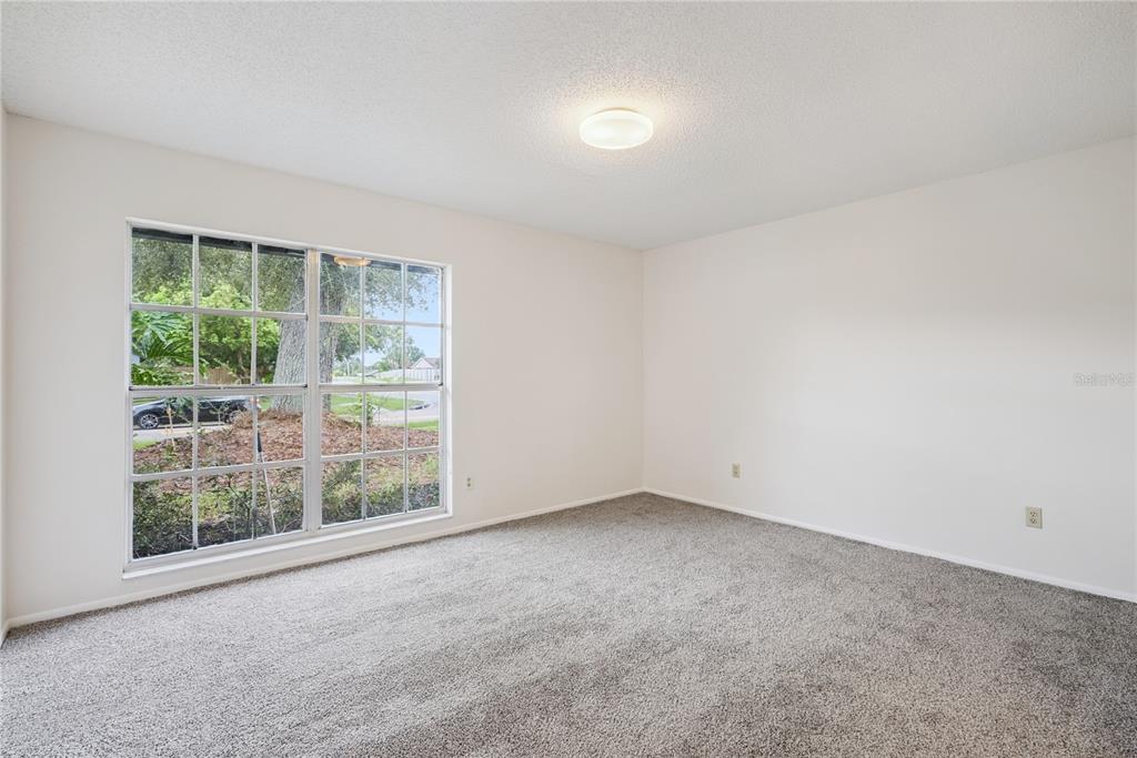 An empty bedroom features beige walls, gray carpeting, a ceiling light, and a large window — 1298 MADELENA AVENUE, WINTER SPRINGS, FL