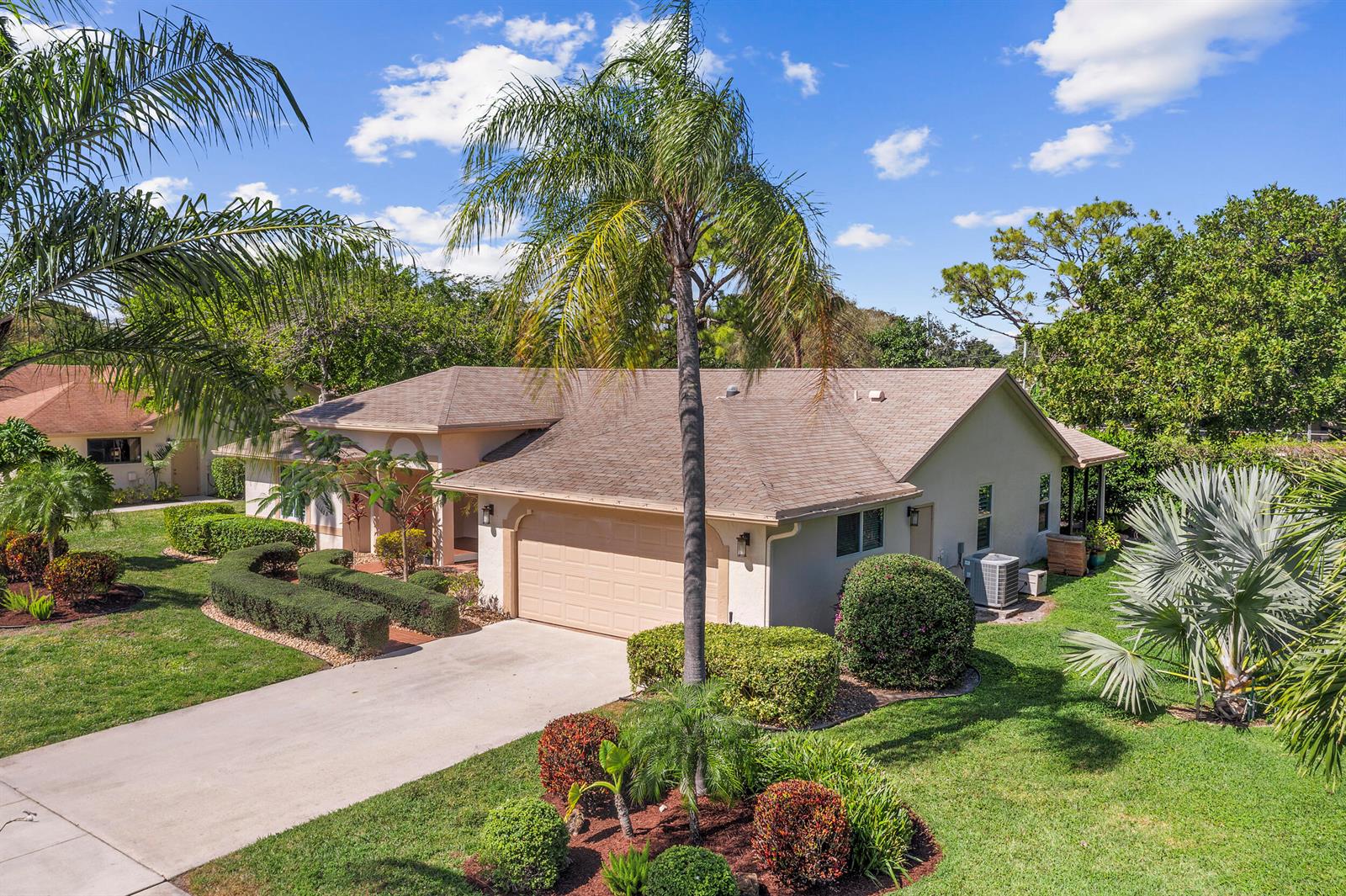 An exterior view of a single-story house with a tan garage and a palm tree — 2685 Riviera Drive, Delray Beach FL 33445, DELRAY BEACH, FL