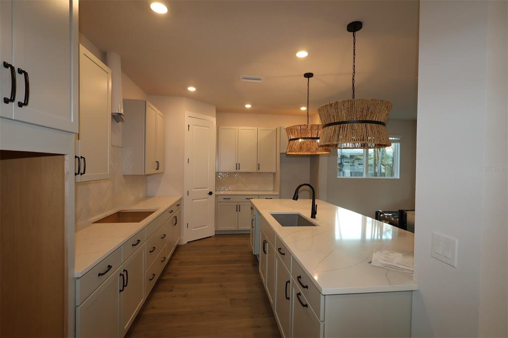 A modern kitchen features white cabinetry, a large island with three stools, and pendant lighting — 4008 W LEMON STREET, TAMPA, FL