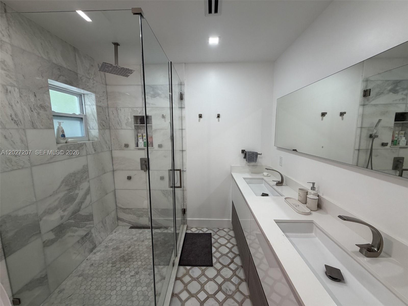 A modern bathroom features a glass-enclosed marble shower, a double vanity, and patterned floor tiles — 665 Allendale Rd, Key Biscayne FL 33149, KEY BISCAYNE, FL